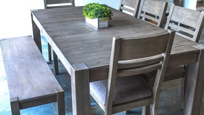 Una mesa de comedor de madera con seis sillas, un banco y una planta en maceta.