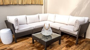 Un sofá modular con una mesa de centro de vidrio y una cesta tejida.