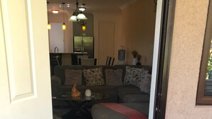 A living room with a sofa, a coffee table, and a decorative rug. There is a door leading to another room.