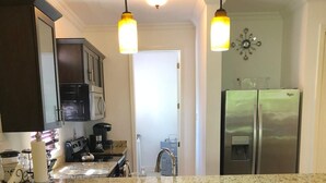 A kitchen with dark wooden cabinets, a granite countertop, and three bar stools.