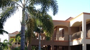 A multi-story hotel with a central courtyard, palm trees, and a brick pathway.