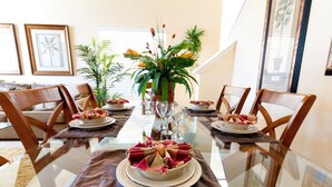 A dining table set for a meal with chairs, a centerpiece, and framed artwork on the walls.