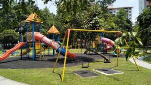 A playground with slides and swings, surrounded by grass and trees.