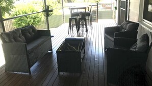 A covered outdoor seating area with wicker furniture and a table.