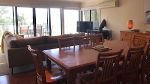 Uma sala de jantar com uma mesa e cadeiras de madeira, um sofá, uma televisão e uma lareira.