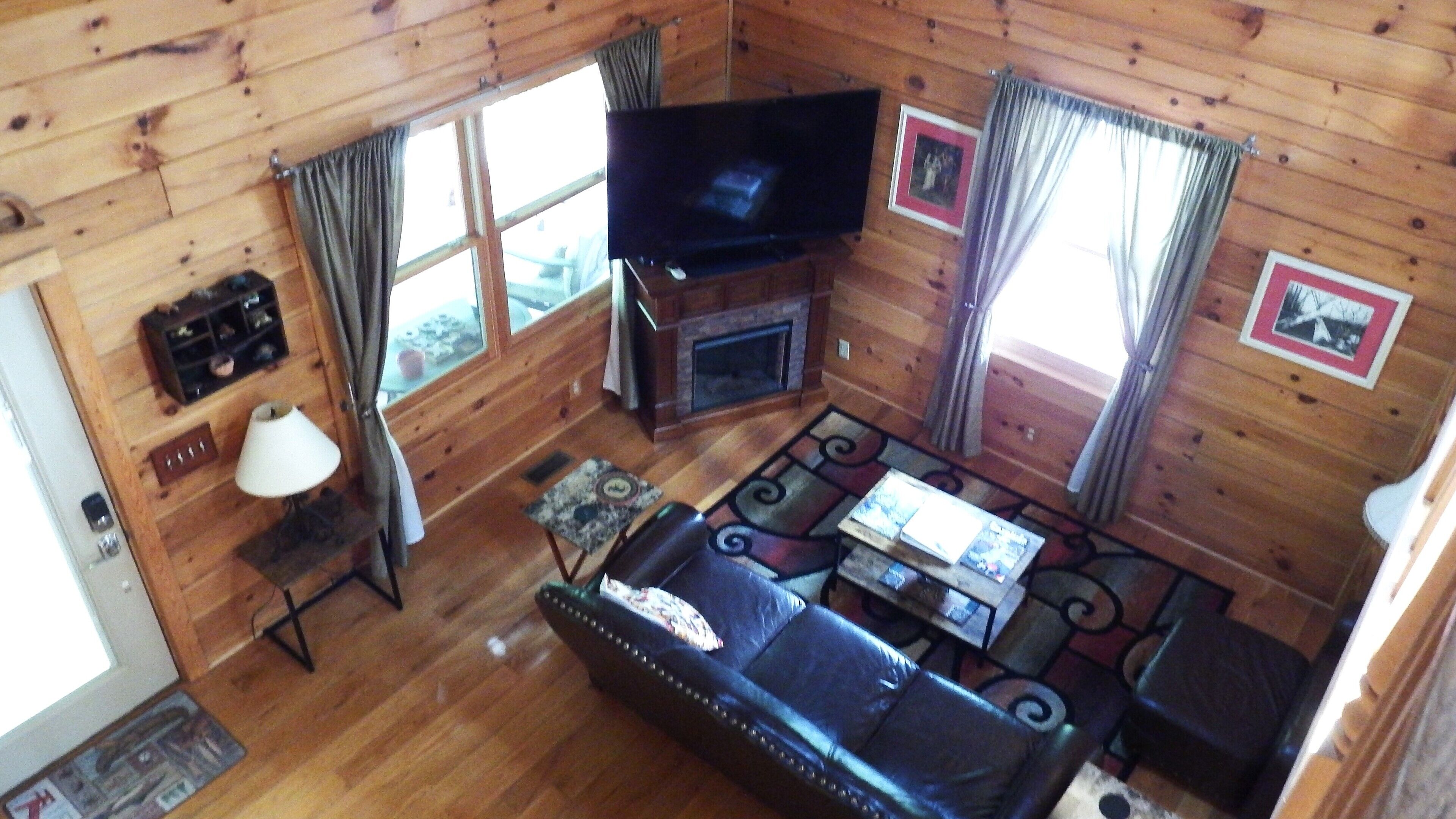 A cozy cabin interior with a fireplace, a flat-screen TV, a leather sofa, and a coffee table.