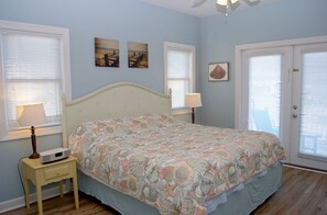 A bedroom with a bed, two bedside lamps, a nightstand, and a door with a window.