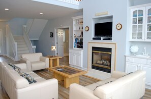 A living room with a fireplace, a television, and a staircase.