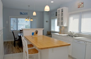 A kitchen with a wooden island, white cabinets, a built-in dishwasher, and pendant lighting. - Patient Tide Beautiful 3 BR Ocean View Home; Community Pool & Tennis Courts (North Topsail Beach)
