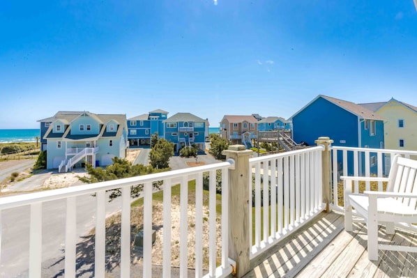 A coastal residential area with houses featuring balconies and a wooden deck. - Patient Tide Beautiful 3 BR Ocean View Home; Community Pool & Tennis Courts (North Topsail Beach)