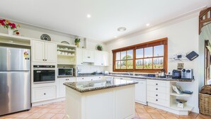 Una cocina moderna con armarios blancos, encimera de granito, ventana grande y horno empotrado.