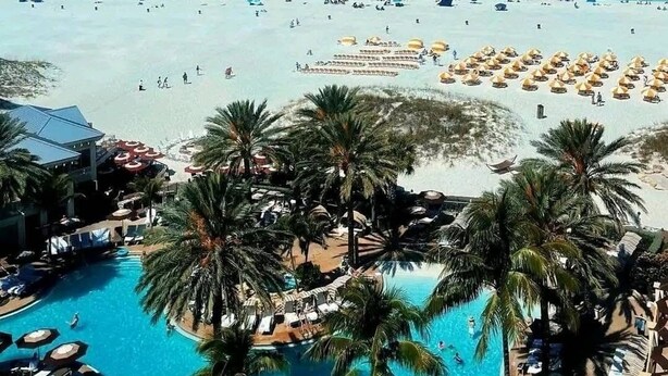 Ein Resort mit großem Pool, Strandbereich und Palmen.