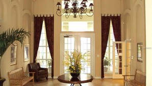 Eine großzügige Lobby mit einem runden Tisch, zwei Stühlen, einer Kronleuchter und einem Blumentopf.