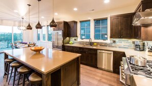 A modern kitchen with a large island, dark wood cabinets, stainless steel appliances, and pendant lighting. - Friendcation in Bend ~ hot tub ~ bunk beds ~ resort pool + amenities ~ golf ~🐶 (Bend)