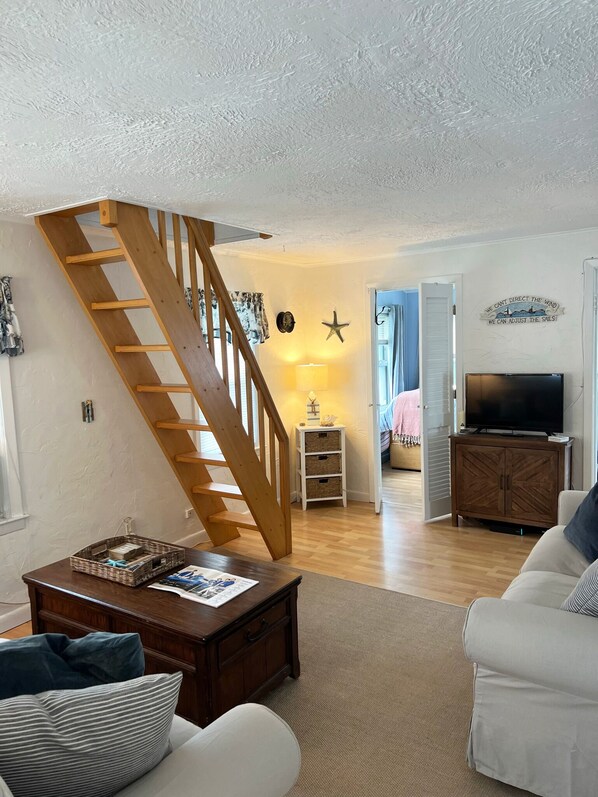 A living room with a wooden staircase, a television, and a cozy seating area.