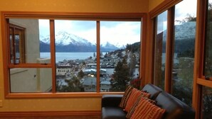 A room with a large window offering a view of a town and mountains. - Expansive home in the Heart of Queenstown with Stunning Views. (Queenstown Hill)
