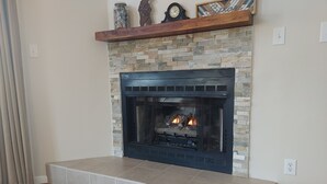 A fireplace with a stone surround and a black front panel, flanked by a wooden bench. - The Octagon House: long-range views, fireplace, easy access, close to town (Franklin)