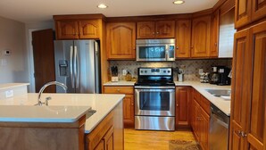 A modern kitchen with wooden cabinets, stainless steel appliances, and a central island with a sink. - The Octagon House: long-range views, fireplace, easy access, close to town (Franklin)