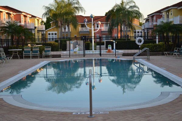 Relax by the rectangular pool surrounded by lounge chairs and a small table, with palm trees adding to the tropical ambiance.