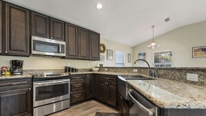 A modern kitchen with dark wood cabinets, stainless steel appliances, granite countertops, and a large island with a sink. - View the Beach from your porch.  
Best location, 5 blocks to downtown  (Biloxi)