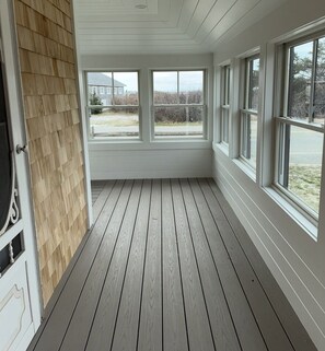 Une pièce dotée d’un plancher en bois, de murs blancs et de nombreuses fenêtres.