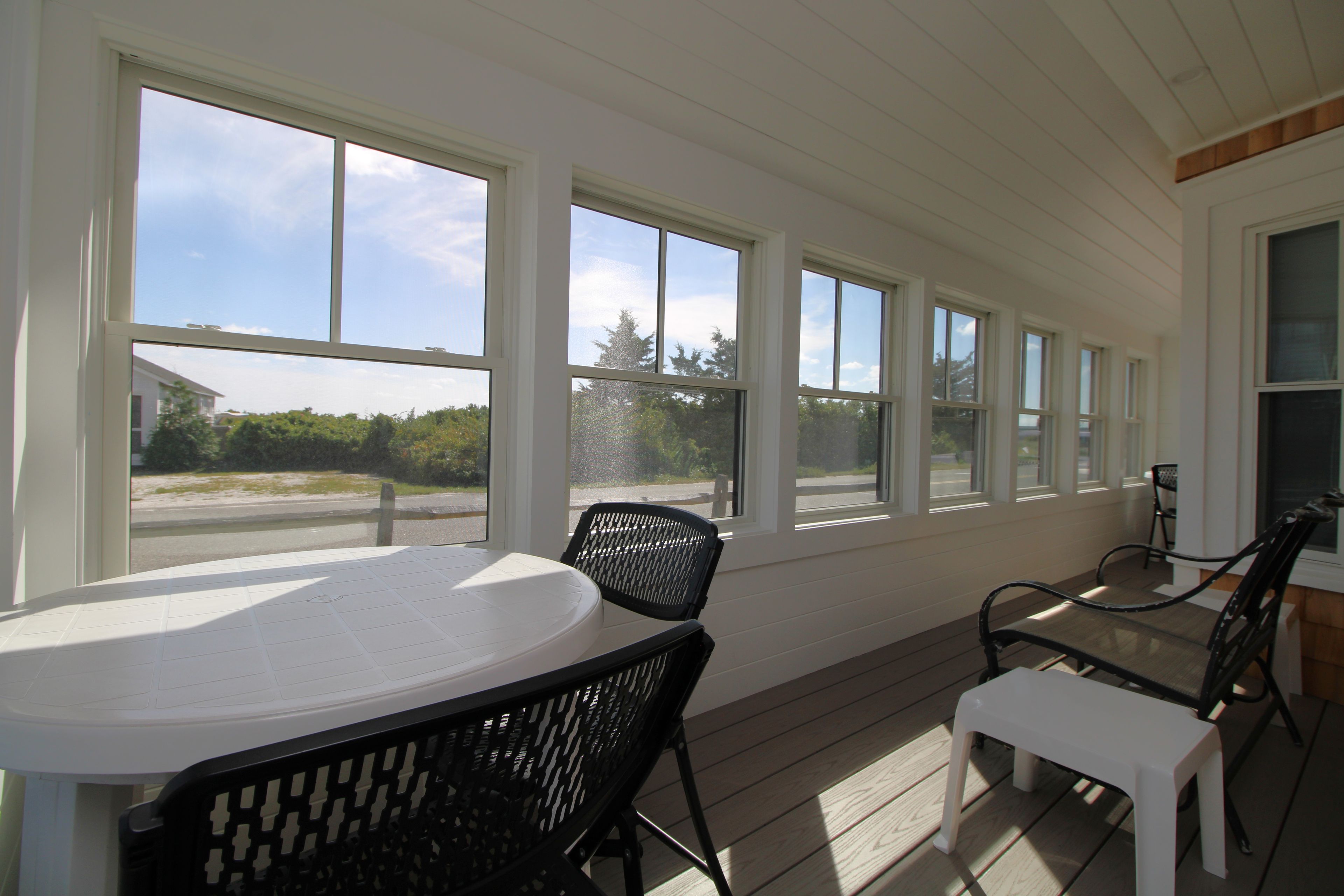 A sunroom with a table and chairs, large windows, and a view of the outdoors.