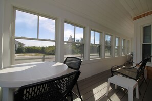 A sunroom with a table and chairs, large windows, and a view of the outdoors.