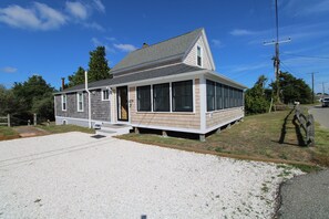 A single-story house with a sloped roof, a front porch, and a gravel driveway.