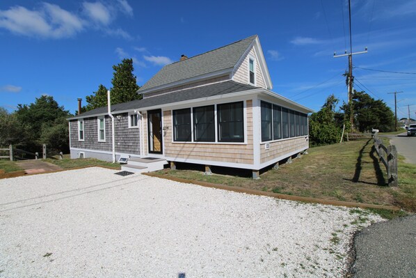 A single-story house with a sloped roof, a front porch, and a gravel driveway.