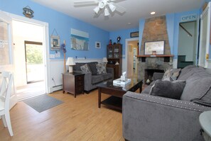 A living room with a fireplace, a sofa, a coffee table, and a door leading to the outside.