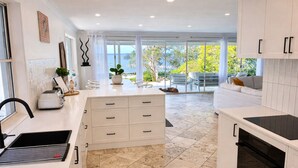 Una cocina moderna con armarios blancos, una estufa negra y un ventanal con vistas al exterior.