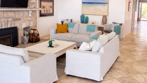 Una sala de estar con chimenea, televisión y un cuadro de una playa.