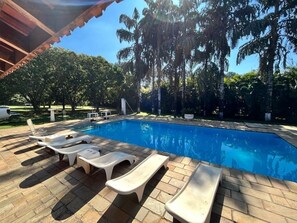 En swimmingpool med liggestole og et overdækket område.