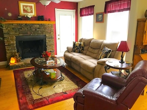 Una sala de estar con chimenea, un sofá, una mesa de centro y un sillón de cuero.