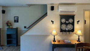 Una habitación acogedora con una mesa de madera, dos lámparas, un aparador decorativo y una escalera.