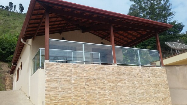 Un edificio con fachada de piedra, un balcón con barandilla de vidrio y una antena parabólica.