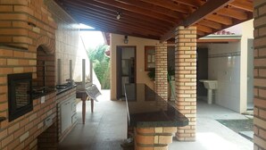 Una cocina con horno de ladrillo, un lavamanos y techo de madera.