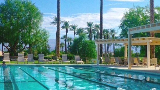Une piscine à l’eau d’un bleu cristallin, entourée de chaises longues et de palmiers.