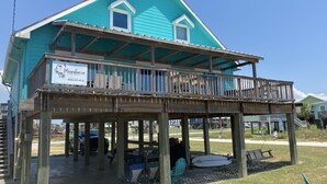 A turquoise two-story building with a wooden deck and a sign for 'Moondancer Beach House' and 'Vacation Rental'. - Location, Location, Location! (Surfside Beach)