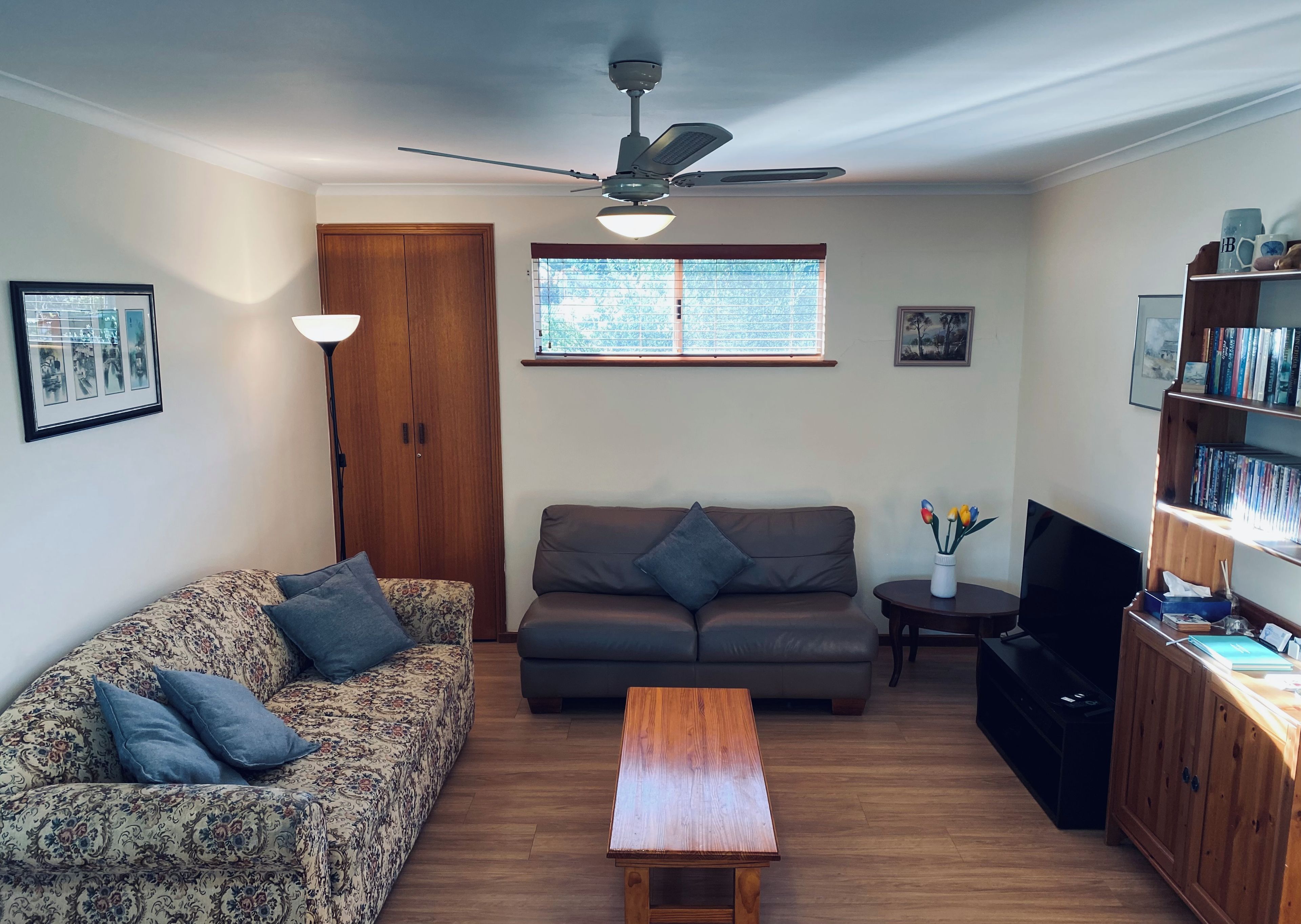 Ein Wohnzimmer mit einer Couch, einem Couchtisch, einem Fernseher und einem Bücherregal.