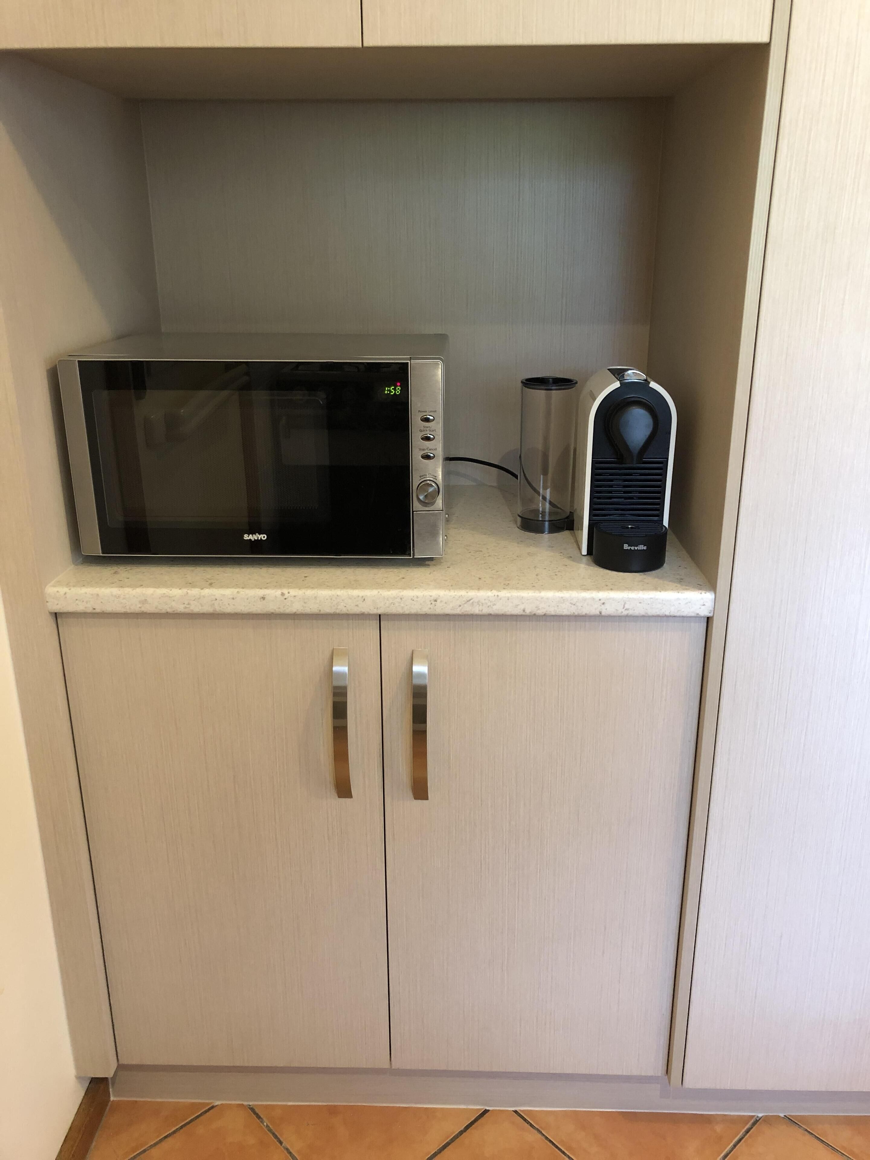 Eine Mikrowelle und eine Kaffeemaschine von Breville auf einer Küchenarbeitsplatte.