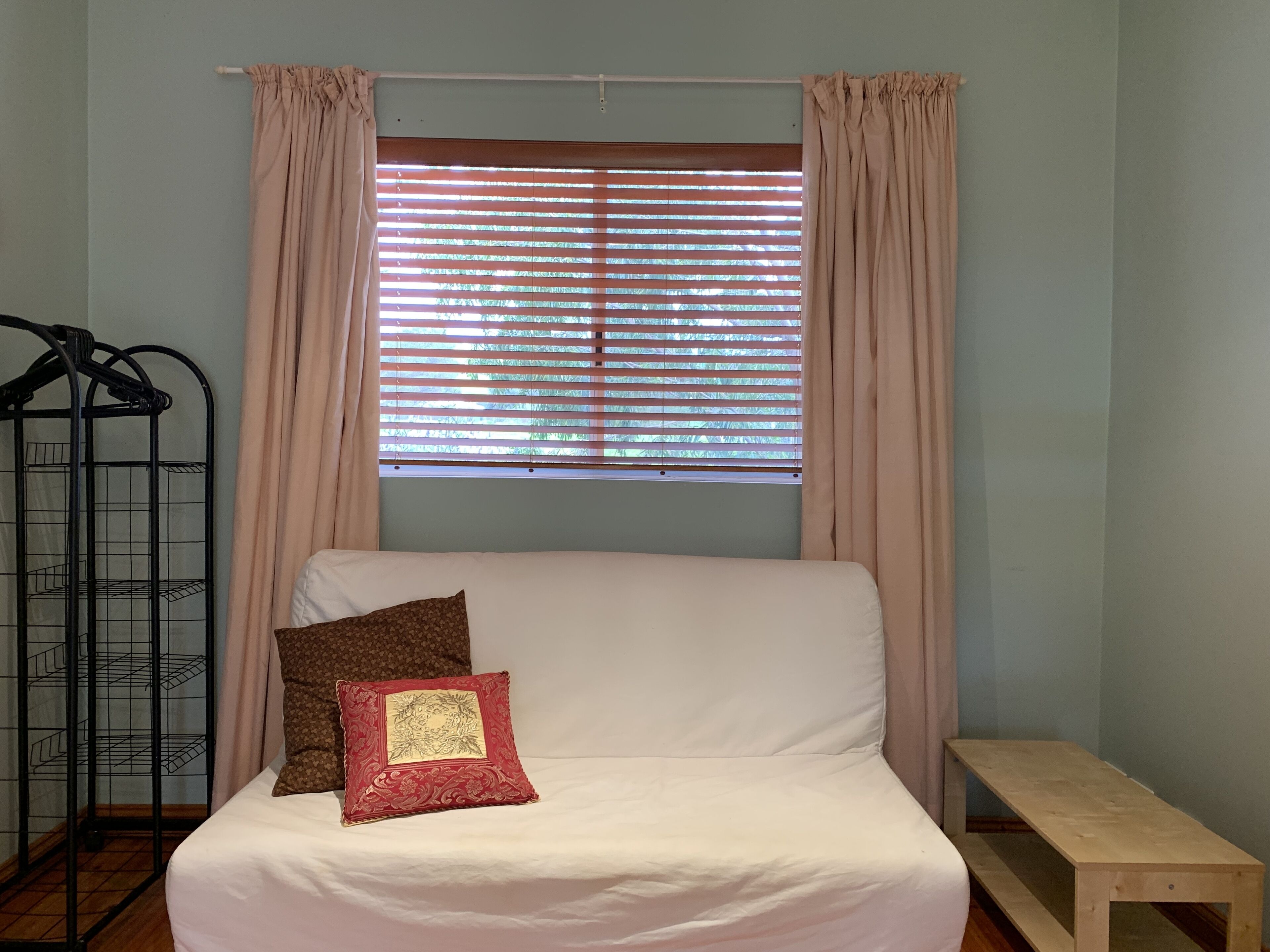 A bed with white bedding, a single decorative pillow, and a wooden bench.