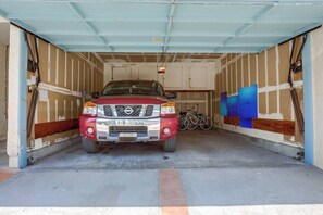 Camioneta roja estacionada dentro de un garaje, con una bicicleta a la derecha.