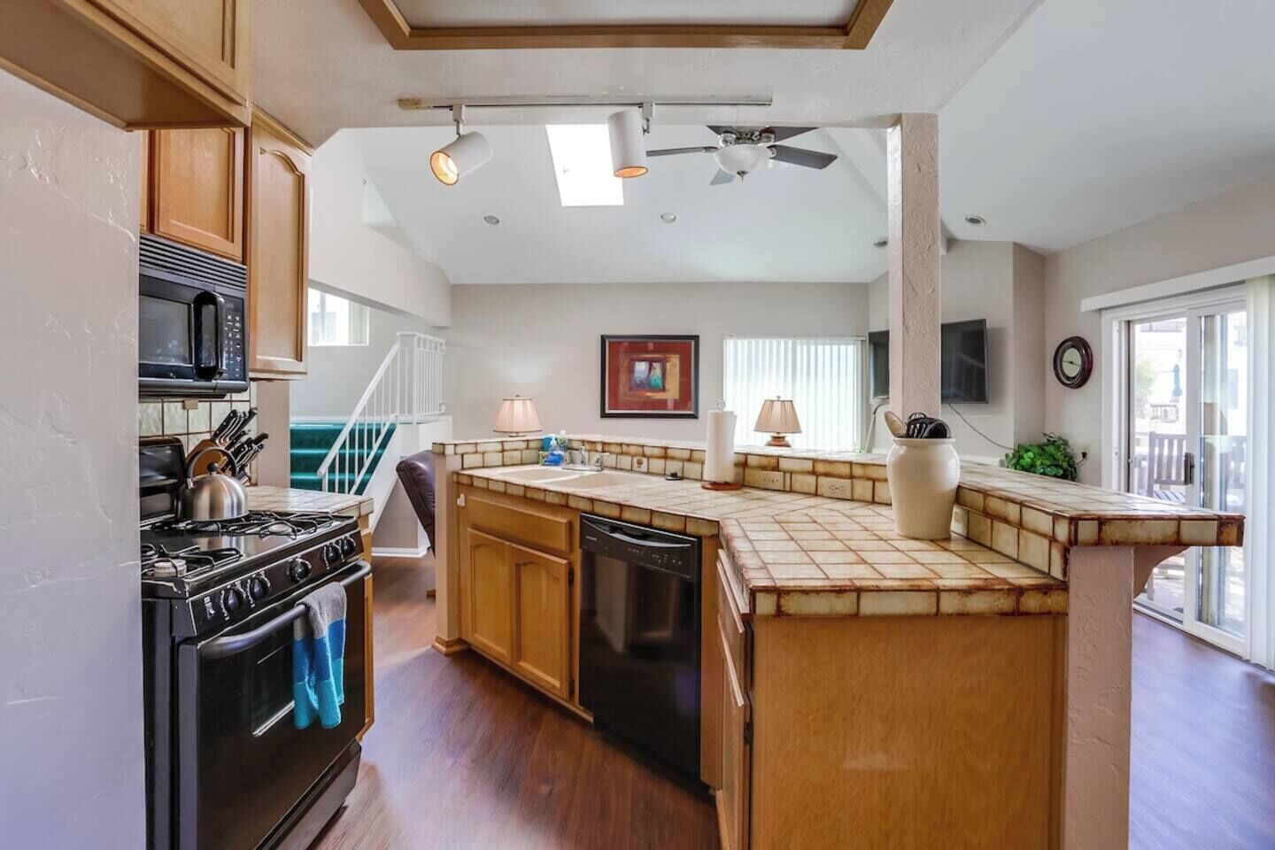 A kitchen with a central island, a stove, microwave, and dishwasher. There is a staircase leading to an upper level.
