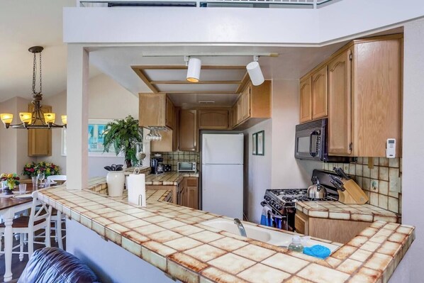 Een moderne keuken met een centraal eiland, houten kastjes, een magnetron en een fornuis.
