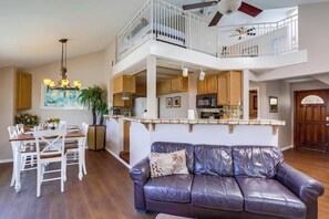 A spacious living area with a leather sofa, dining table, and chairs, a kitchen with modern appliances, and a balcony with a railing. - Balcony Ocean view, heart of MB, garage and bikes (San Diego)