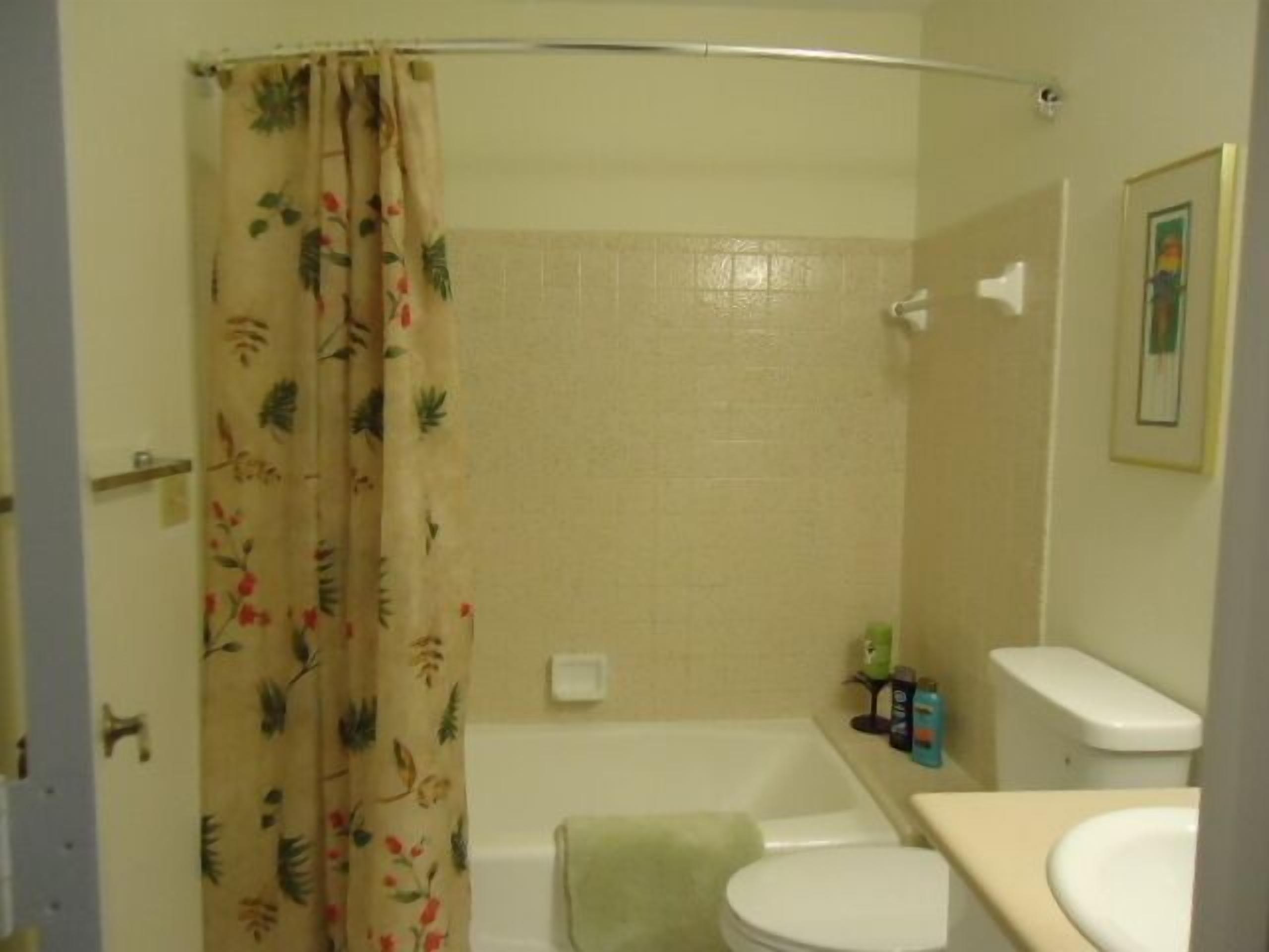 Un bagno con tenda doccia, vasca, WC e lavandino.