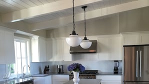 Una cocina amplia con muebles blancos, un refrigerador de acero inoxidable y una isla de madera con un florero.