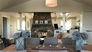 Amplia sala de estar con chimenea de piedra, muebles de mimbre y un comedor con mesa de madera.