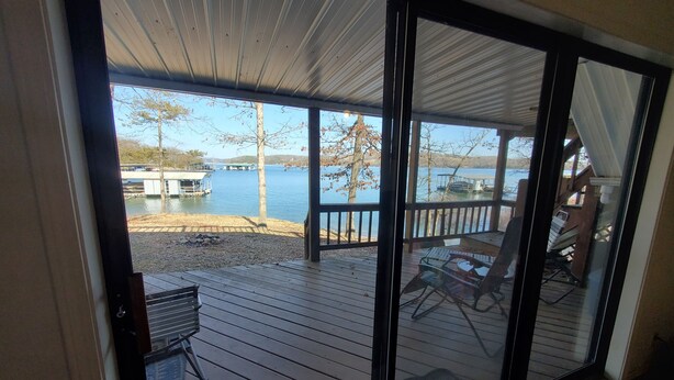 A view from a room with a sliding glass door to a deck overlooking a lake with docks and boats. - BERGS NEST-Lakefront Home-Incredible Shoreline Close to House!  (Garfield)